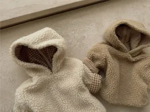 Detail shot of cozy fleece baby hooded jackets with plaid lining in neutral cream and khaki tones.