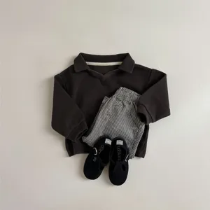 Toddler casual clothing set detail, vintage striped pants and brown polo shirt, cozy baby apparel.