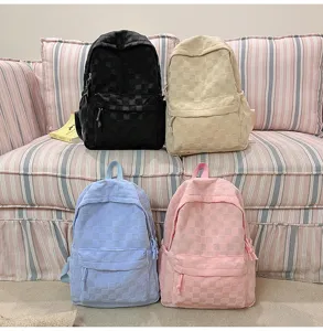 Close-up detail of textured checkered backpacks in multiple pastel colors arranged on sofa.