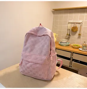 Pink checkered backpack detail showing textured fabric, front pocket and straps.