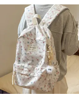 Detailed close-up view of the floral lace backpack featuring cute charms and front pocket.