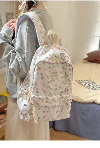 Floral pattern backpack detail showing fabric texture, front pocket and cute doll pendant.