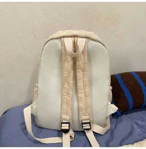 Detailed view of the beige backpack showing back straps, adjustable buckles, and checkered texture.