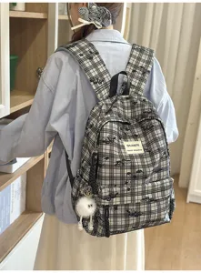 Detailed view of a trendy plaid canvas backpack featuring cute cartoon prints and a front label.