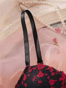 Close-up detail of black and red floral embroidered lace bra strap and cup texture display.