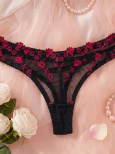 Detailed shot of sexy black lace sheer thong panties with exquisite red floral embroidery.