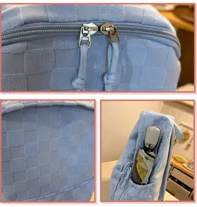 Light blue checkered backpack detail view showing soft woven texture, dual zippers, and side pocket.