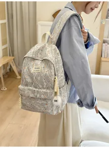 Close-up detail of the floral lace backpack with front pocket, cute pendant and straps.