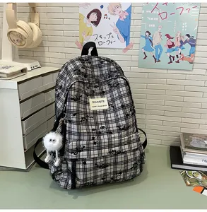 Close-up detail of the stylish black and white plaid backpack with fuzzy keychain.