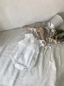 Gedetailleerd overzicht van witte baby meisje zomer spencer gesmokte taart romper, fijn jacquard stof.