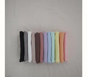 Detailed view of multiple rolled colorful baby rompers and clothes neatly arranged on surface.