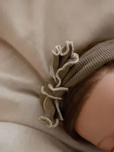 Detailed close-up view of infant ribbed knit headband featuring delicate ruffle trim.