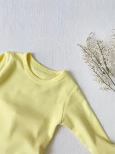 Baby yellow long sleeve top detail shot, soft cotton infant basic wear for spring season.