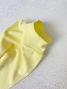 Soft yellow baby bodysuit fabric detail close-up, comfortable cotton ribbed knit texture.