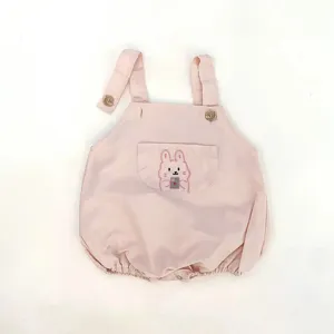 Baby pink strap romper detail featuring cute cartoon rabbit embroidery, buttons, and soft fabric.