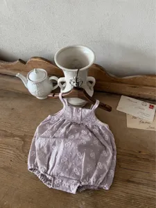 Close-up of baby girl vintage floral embroidered cotton strap romper, delicate details.