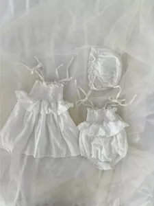 Witte zomerse babykleding set met gesmokte bandtop, broekje en schattig bijpassend mutsje.