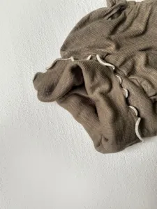Infant autumn wear clothing detail view, ribbed knit fabric texture with lettuce edge design.