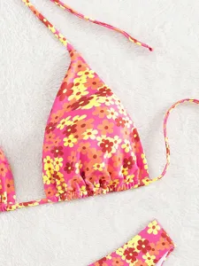 Detailopname van een roze retro bloemenbikinitop met halterbandjes en een kleurrijke print.