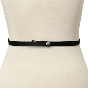 Primo piano dettagliato di una sottile cintura in pelle nera minimalista con bottone a pressione.