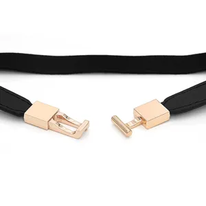 Women elastic thin dress belt detail view, minimalist black strap with rose gold metal clasp.