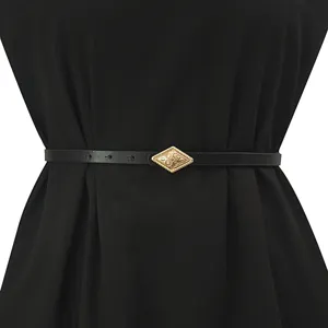 Close-up detail of women's thin black belt with a decorative gold diamond buckle accessory.