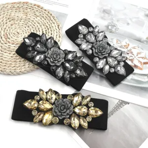 Detail shot of sparkling rhinestone elastic waist belts with floral design, versatile accessory.
