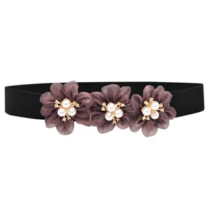 Detail van de elastische damesceintuur met drie stoffen bloemen, parels en strass steentjes.