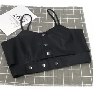 Dettaglio di un top corto nero in ecopelle con bottoni a pressione e spalline fini.