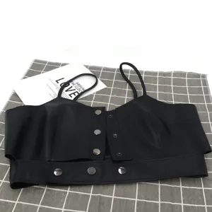 Dettaglio ravvicinato del crop top in pelle PU nera con bottoni a pressione metallici.