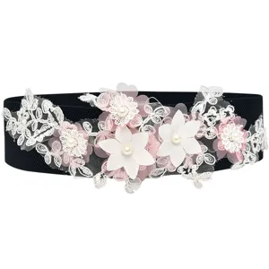 Detail view of black elastic waist belt decorated with white pink lace flowers and pearls.