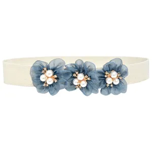 Detail van elastische damestailleband met blauwe organza bloemen, parels en stras.
