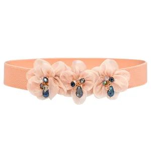 Close-up of peach pink elastic waist belt with triple floral rhinestone crystal details.