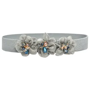 Close-up detail of grey elastic waist belt with three fabric flower crystal beads.