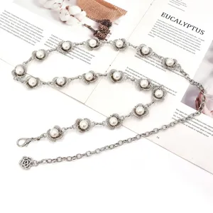 Détail de chaîne de taille en métal argenté avec pendentifs perles, accessoire de mode pour femmes.