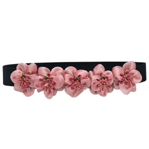 Close-up detail of the pink fabric flower decorations and black elastic waist belt design.