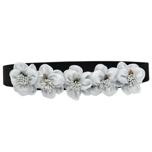 Detail view of a black elastic waist belt featuring five elegant silver fabric flowers.