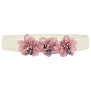 Elegant women elastic waist belt detail featuring pink sheer flower and sparkling rhinestones.