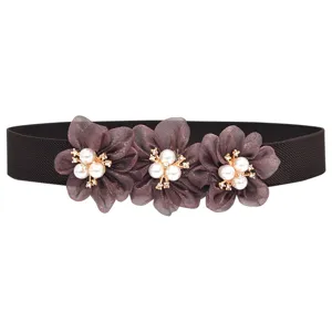 Detailopname van de delicate bloemen elastische riem met parel- en strass-steentjes.