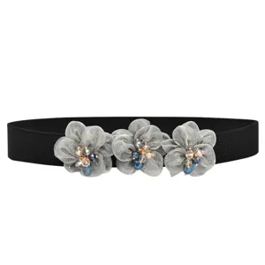 Close-up detail of shimmering silver fabric flowers and beaded center on black elastic waist belt.