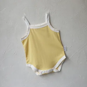 Baby summer yellow strap bodysuit detail, soft cotton infant romper flat lay close up.