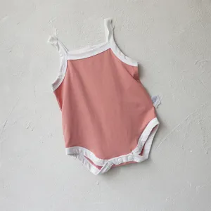 Close-up details of the pink baby romper featuring white trim, straps, and bottom snap closure.