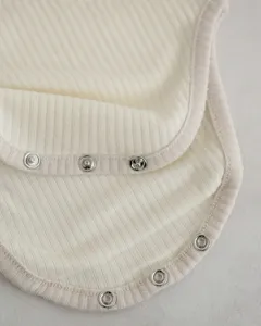 Close-up detail of ribbed cotton baby romper fabric with contrast trim and metal snaps.