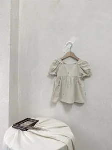Detail view of girls summer short sleeve embroidered cotton dress hanging on wall in minimalist style.