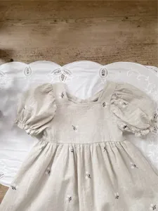 Girls summer linen dress detail, cute puff sleeves and delicate floral embroidery, soft fabric.