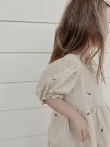 Detail view of toddler girls cotton dress with puff sleeves and delicate floral embroidery.