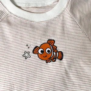 Baby summer striped t-shirt with cute cartoon fish print, soft cotton fabric detail.