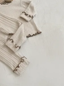 Detailed view of the baby ribbed long sleeve top and pants set with brown lettuce edge trim.