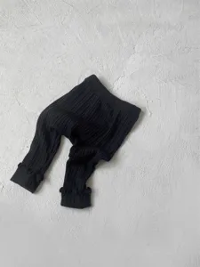 Black ribbed baby pants detail shot, featuring cute ruffle cuffs and comfortable knit fabric.