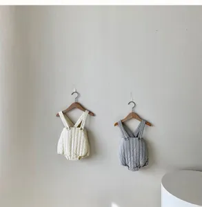 Detailed view of thickened quilted baby romper straps in cream and grey hanging on display.